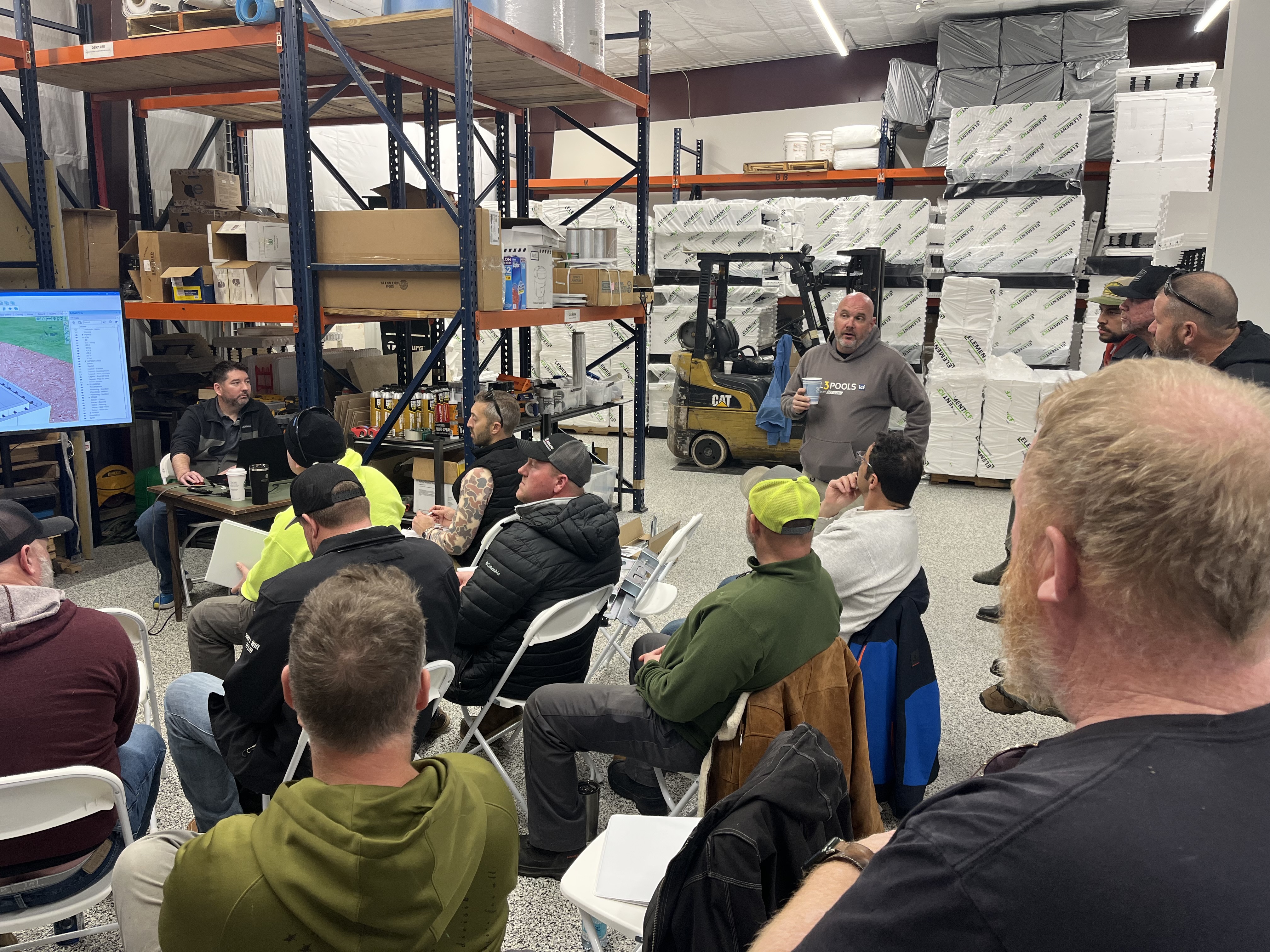 Aaron King teaching a class with ICF blocks and builders gathered around in the warehouse